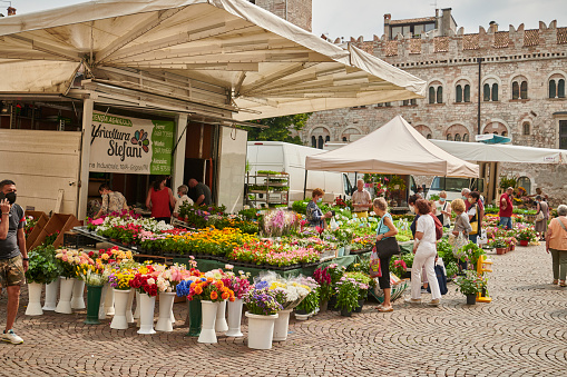 Trento city in the district Alto Adige the twenty second of July 2021. Incidental people outdoors during a hot period. Images from Northern Italy. People buying flowers at the market place