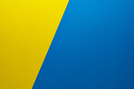 Background of two colors yellow and blue. Sheets of blank yellow and blue paper with texture separated by a sloping border.
