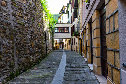Behind the road that lies alongside the port, lies a cobbled alley with deep stone wall that runs parallel to the port road, with houses arching over the street.