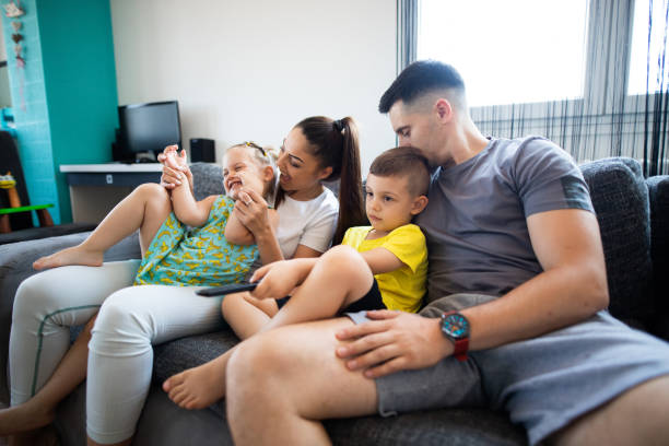 istock Cheerful family with two young childrens on sofa 1330770042
