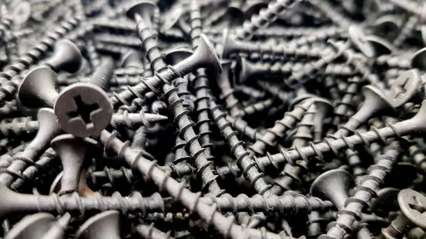 Photo of steel screws, metal screw, iron screw, screws as a background, wood screw. Iron or metal screw nails stack industrial building industry background