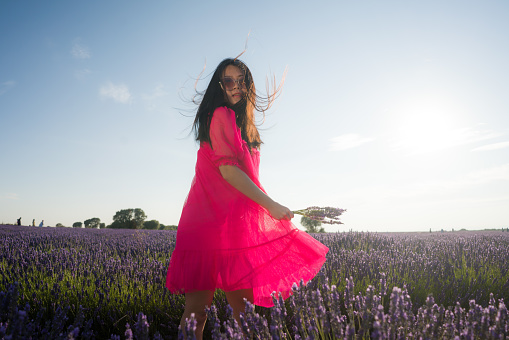 young Asian woman outdoors at lavender flowers field - happy and beautiful Japanese girl in sweet Summer magenta dress enjoying holidays relaxed on purple floral meadow