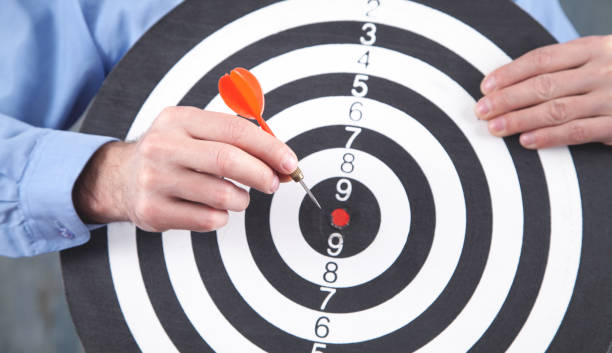 istock Male hand holding dart arrow in target dartboard. 1330773708
