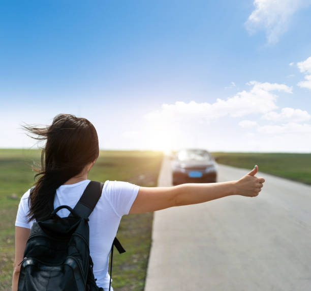 istock Woman standing on roadside with thumb up 1330774698