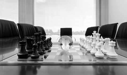 Chess pieces and glass earth globe on office table.