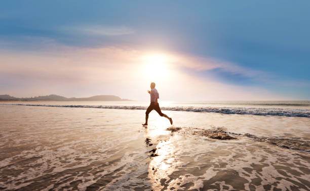 istock Man running on the beach at sunset 1330775009