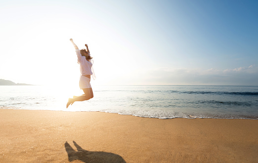 Happy woman jumping on the beach.