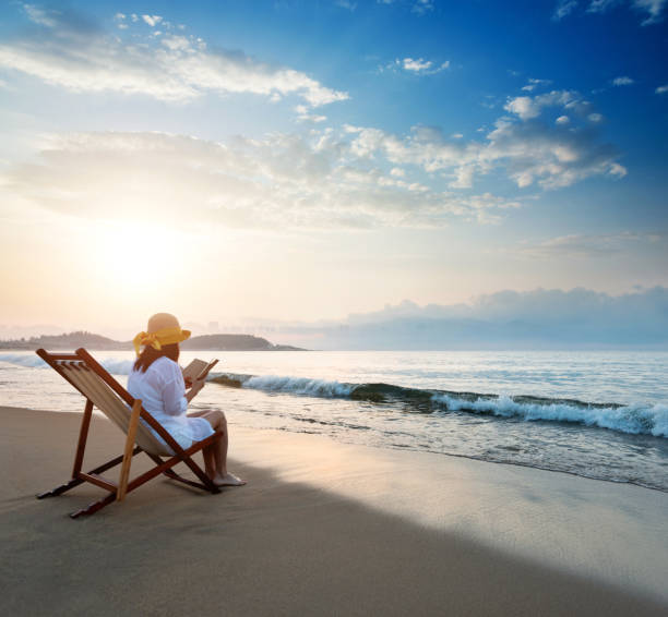 istock Woman reading a book by the sea 1330775043