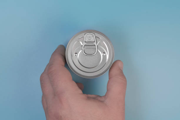 istock The hand takes a tin can. On a blue background. Close-up 1330777217