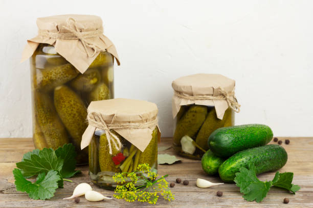 istock Pickled cucumbers in glass jars on light background 1330778611