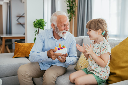 Image of senior man - grandfather and his granddaughter having fun at home