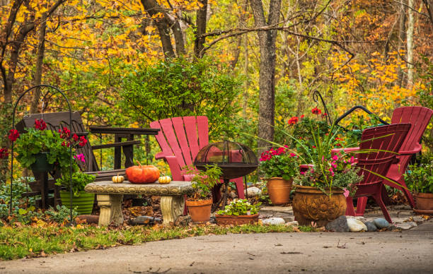 View of group of chairs, grill and potted plants in Midwestern front yard in autumn View of group of chairs, grill and potted plants in Midwestern front yard in autumn; red maples in background fall lawn stock pictures, royalty-free photos & images