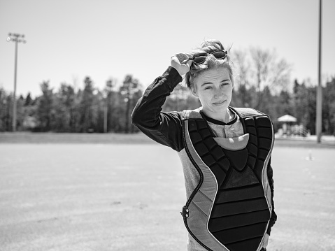 Portrait of young Transgender woman playing baseball outdoor at the baseball field. She is  dressed in casual clothes with baseball gear.  Exterior of public baseball field in the park.