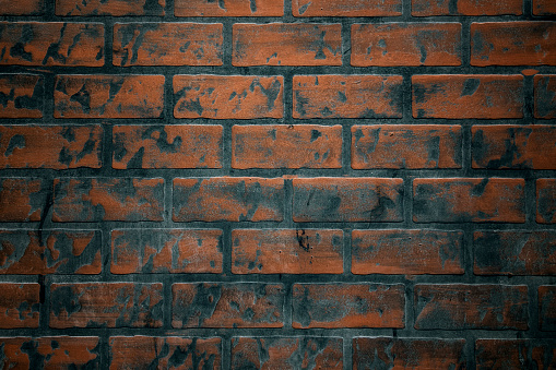 The orange old brick wall of the ancient building is dirty with black stains, with laterite stones on top for background