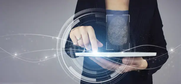 Biometrics identification. White tablet in businesswoman hand with digital hologram Fingerprint scan sign on grey background. Immersive technology future and cybernetic.