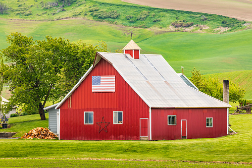 Garfield, Washington, USA. May 24, 2021. A red barn with an American flag in the Palouse hills.