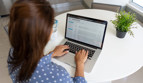 Mujer teletrabajando y leyendo su correo electrónico en una computadora portátil en casa photo