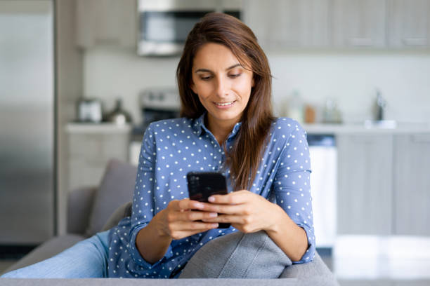 istock Woman relaxing at home texting on her cell phone 1330800018