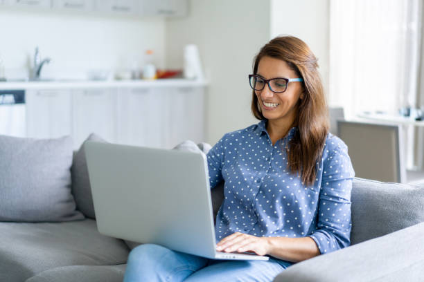 istock Happy woman telecommuting at home using her laptop computer and smiling 1330800028
