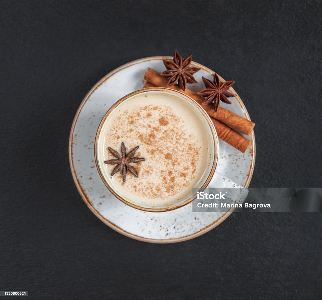 Masala chai tea on a dark background closeup. Traditional Indian hot drink with milk and spices. Top view, flat lay. Masala chai tea on a dark background close up. Traditional Indian hot drink with milk and spices. Top view, flat lay. Chai Stock Photo