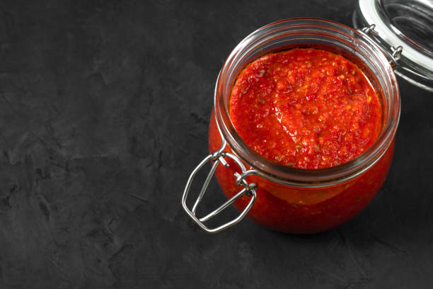 sos harissa. adjika. gorący sos chili w słoiku na czarnym tle zbliżenia. kuchnia tunezyjska, gruzi�ńska i arabska. kopiuj miejsce. - tomato sauce jar zdjęcia i obrazy z banku zdjęć