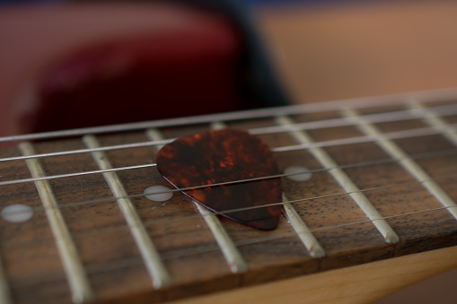 Close-up of a guitar pick in the neck of a guitar, between the strings. Music concept. No one in the picture