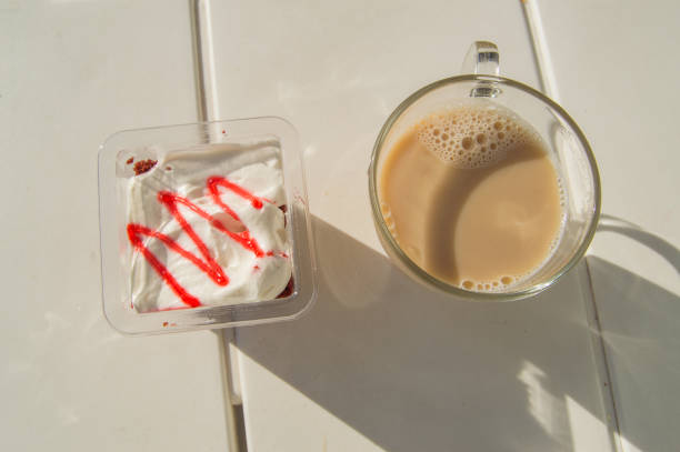 diätfrühstück mit kaffee latte und joghurt mit erdbeermarmelade, blick auf den tisch mit sonnenlicht und schatten - snack coffee instant coffee cappuccino stock-fotos und bilder