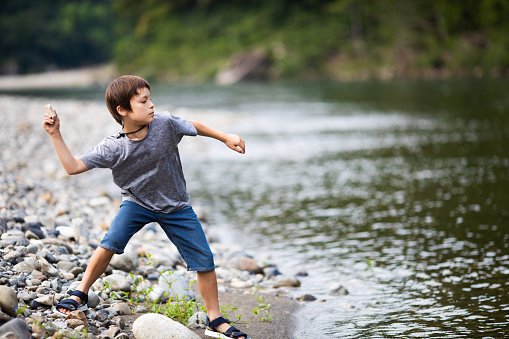 A young boy throwing rocks into a lake.