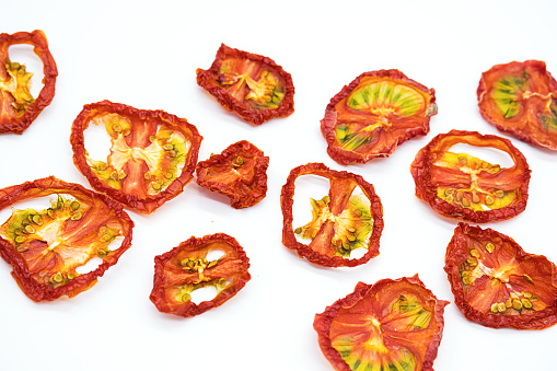 Home cooked, dehydrated tomato. Background of tomatoes chips - superfood, healthy snack.Slices of dried tomatoes on a white background.