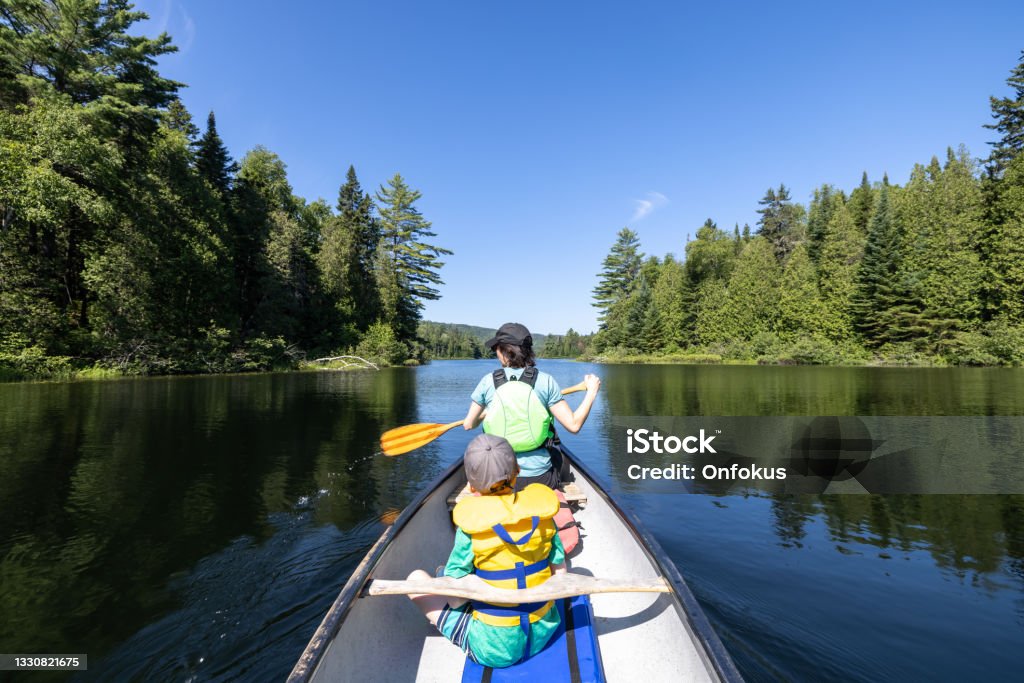 POV Family canoeing on Wapizagonke lake in Parc National de la Mauricie, Quebec, Canada in Summe POV Family canoeing on Wapizagonke lake in Parc National de la Mauricie, Quebec, Canada in Summer. The mother and her son are rowing in directions to Chutes Waber Waterfalls. Canoe Stock Photo