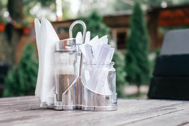 Paper napkins, pepper and toothpicks in metal stand on table in cafe. Summer terrace. Lunch in fresh air. Open terraces in restaurants.