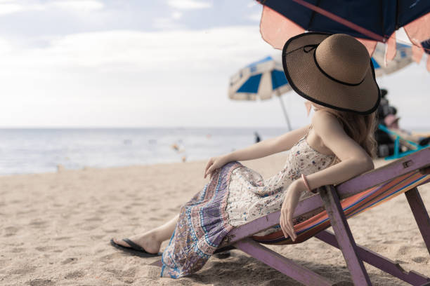 istock woman sitting on deck chair on the beach 1330830881
