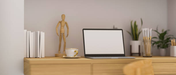 Minimal modern workspace, laptop blank screen on wooden table decor with wood figure, mug, books, tree pot, cozy home interior design, 3d rendering, 3d illustration