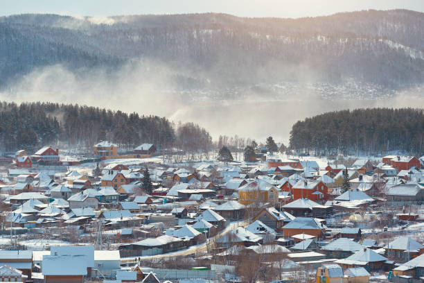 istock Russian village winter. Roofs covered with snow, a Blizzard sweeps in the forest 1330834921