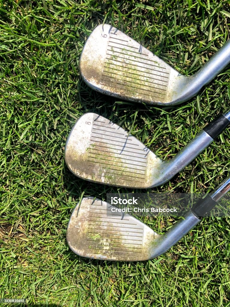 A closeup view of three golf irons with dirty grooves that need cleaning Golf Club Stock Photo
