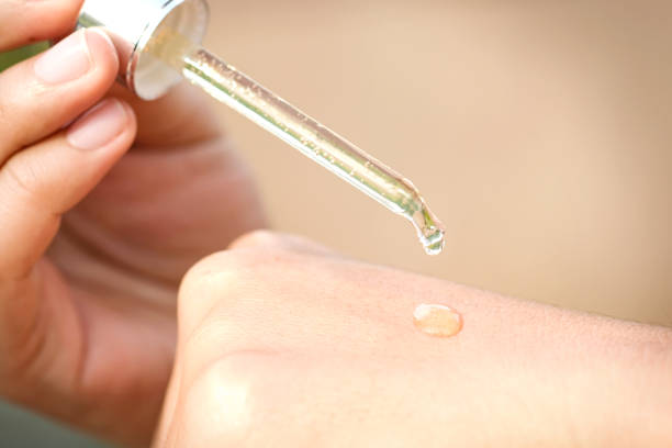 hands of a beautiful woman Dropping serum collagen moisturizer of face into hand soft light background. Protector skin Treatment facial essence oil, Vitamin C. Beauty and spa concept hands of a beautiful woman Dropping serum collagen moisturizer of face into hand soft light background. Protector skin Treatment facial essence oil, Vitamin C. Beauty and spa concept vitamin c stock pictures, royalty-free photos & images