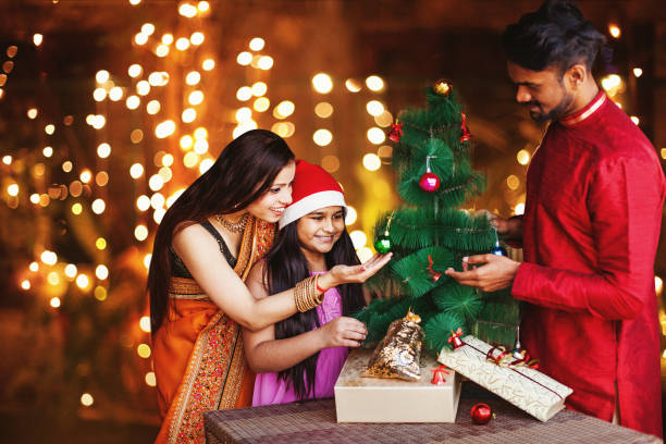 Indian Christmas Beautiful Indian family in ethnic clothes decorating Christmas tree for the New Year celebration at night beautiful traditional indian girl stock pictures, royalty-free photos & images