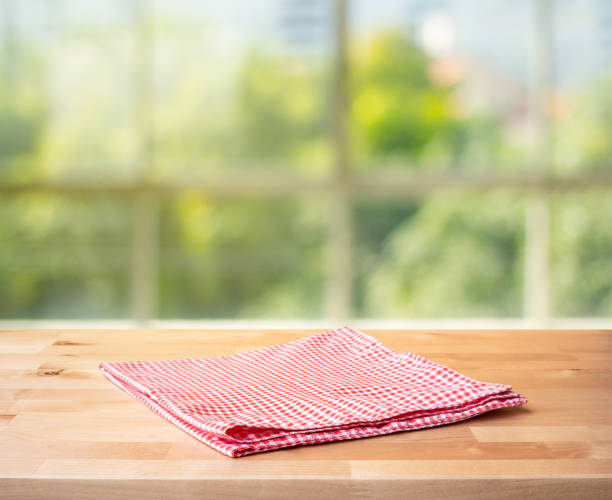 istock Red checked tablecloth on wood with blur green bokeh from window kitchen background.Summer and picnic concepts. 1330842943