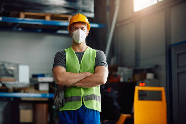 istock Confident male worker wearing protective face mask while standing with arms crossed in a warehouse. 1330843296