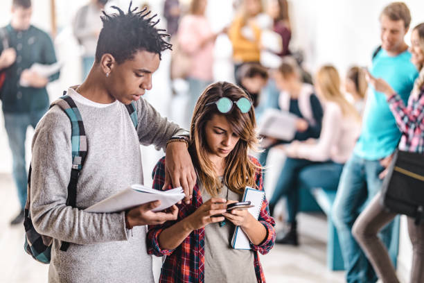 istock Teenage students using mobile phone at school hallway. 1330843664