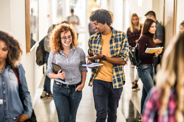 istock Happy college friends communicating while walking through hallway. 1330844345
