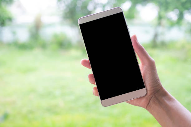 istock Hand holding mobile mock up close up on blur green background. 1330845033