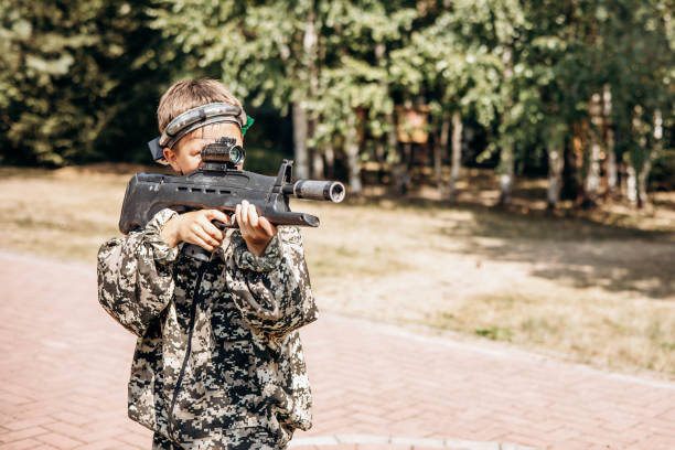 istock Boy looking into the optical sight a weapon. Children playing laser tag shooting game in outdoor. War simulation game 1330845998