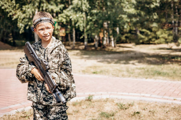 istock Boy with a weapon in his hand playing laser tag shooting game in outdoor. War simulation game 1330846030