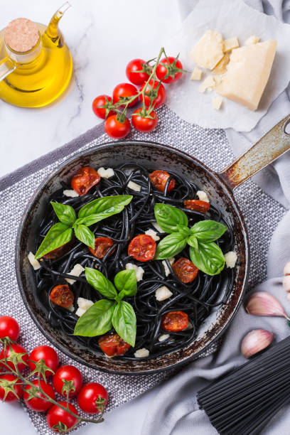 istock Black spaghetti pasta with tomatoes, cheese and basil 1330847129