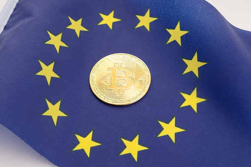 Galicia, Spain, july 22, 2021: Bitcoin coin on European Union flag. Cryptocurrency on Europe