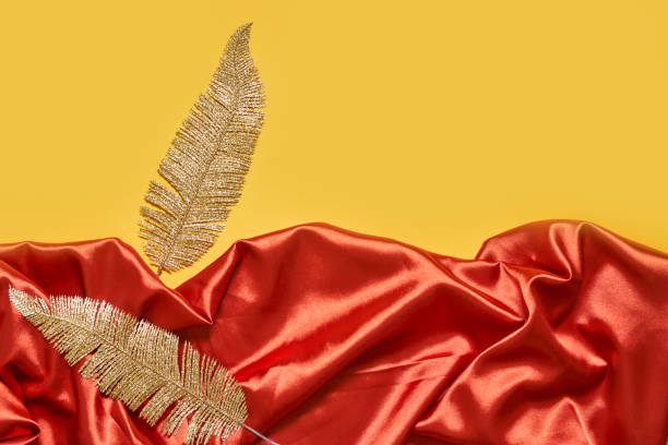 istock Decorative golden leaves on red textile backdrop 1330850083