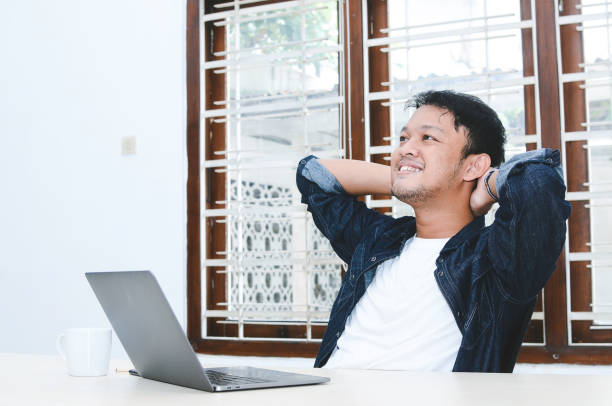 istock Young Asian man relaxing at comfortable office chair hands behind head when work at office 1330853496