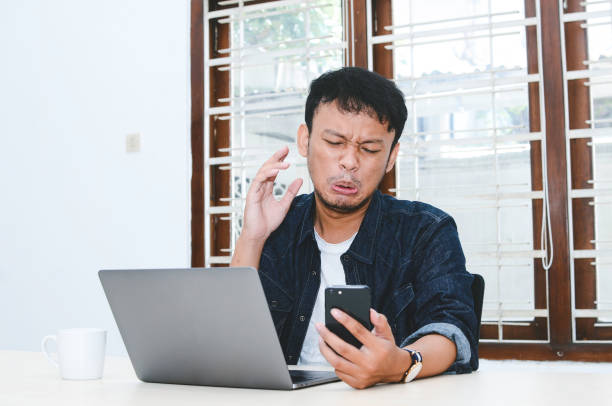 istock Young Asian man feeling sad when work laptop and phone on table. 1330854506