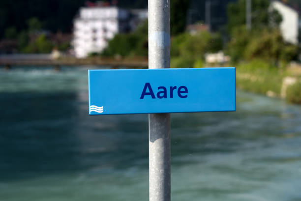 signo del río aare con agua alta en el pueblo de interlaken con puente en el fondo en una soleada tarde de verano. - interlaken switzerland aare river house fotografías e imágenes de stock